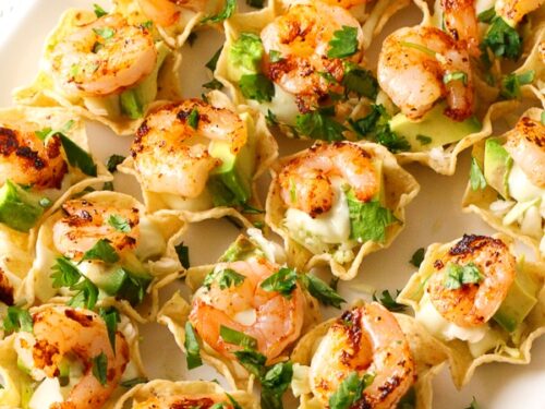 Scoop chips topped with shrimp on a plate