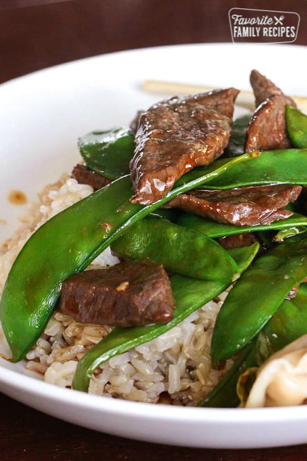 Beef and Snow Peas over rice in a white bowl.