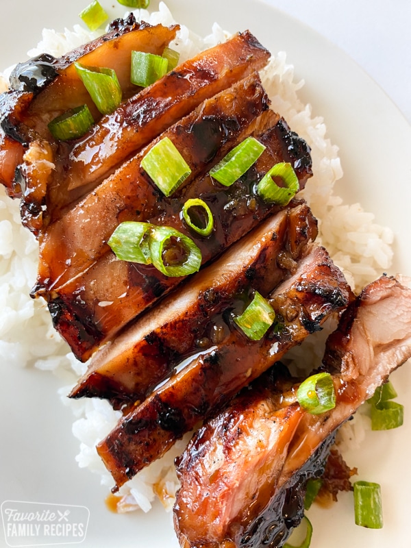 Sliced teriyaki chicken on a bed of rice garnished with green onions