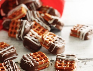 Several Dipped Caramel Pretzel Bites scattered on a white surface.