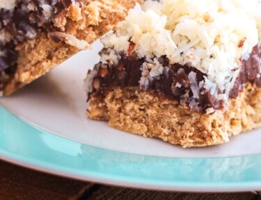 3 Caribbean Coconut Fudge Bars on a white and blue plate on a wood surface.