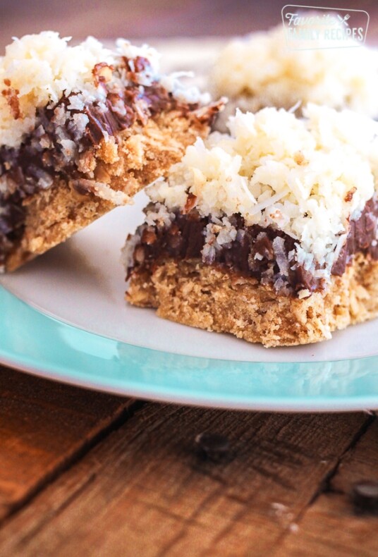 3 Caribbean Coconut Fudge Bars on a white and blue plate on a wood surface.