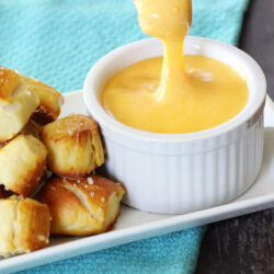 Pretzel bit dipped in cheddar cheese sauce