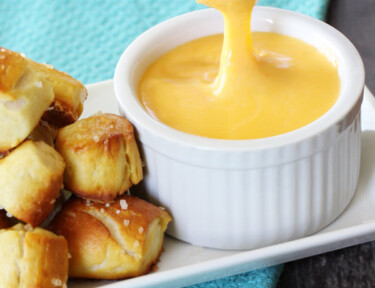 Pretzel bit dipped in cheddar cheese sauce