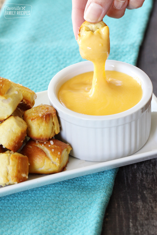 Pretzel bit dipped in cheddar cheese sauce