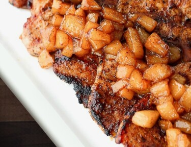 Cinnamon Pork Chops topped with Spiced Pears all on a white tray.
