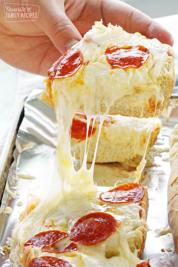 A slice of French bread pizza being bulled up from the pan with cheese stretching from the slice