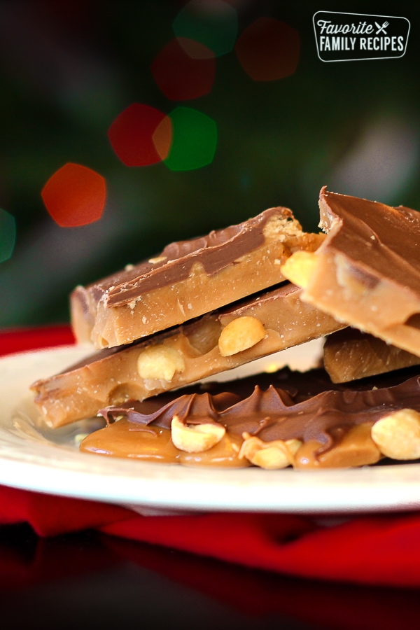 English toffee piled on a white plate with Christmas lights in the background
