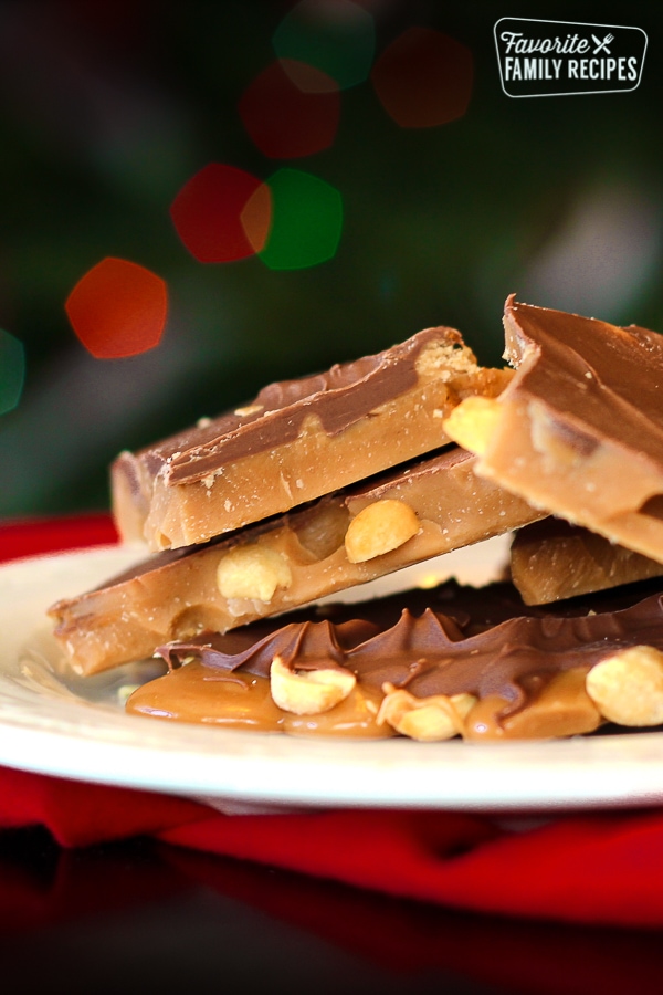 English toffee piled on a white plate with Christmas lights in the background.