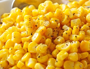 Perfectly cooked frozen corn sprinkled with pepper in a white serving bowl