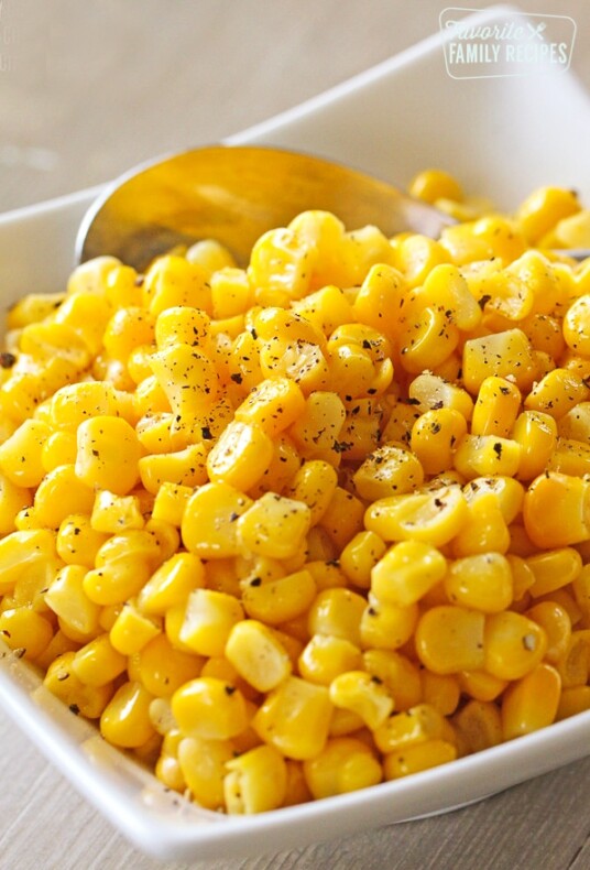 Perfectly cooked frozen corn sprinkled with pepper in a white serving bowl