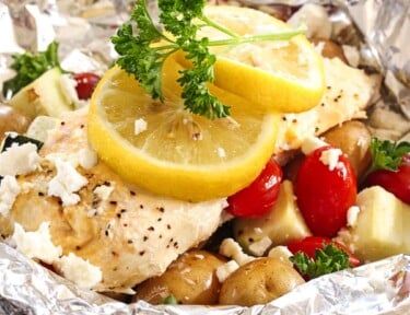 Greek Lemon Chicken Foil Packets with Vegetables and lemon slices topped with a garnish