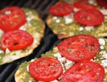 3 Grilled Pesto Pizzas topped with tomatoes on a grill