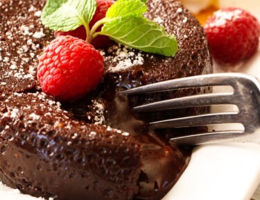 A fork cutting into an Instant Pot Lava Cake topped with raspberries and mint