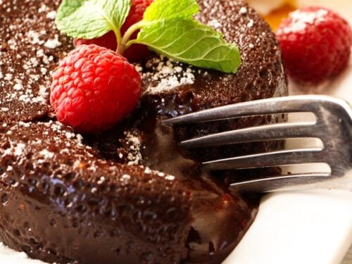 A fork cutting into an Instant Pot Lava Cake topped with raspberries and mint