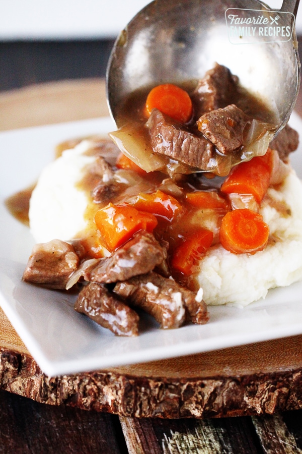 Instant Pot Beef Goulash poured over mashed potatoes on a white plate.