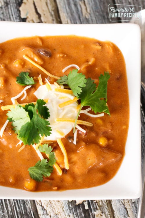 Instant Pot Chicken Enchilada Soup in a white bowl topped with sour cream and cilantro.