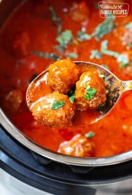 Three Instant Pot Meatballs being scooped from an Instant Pot