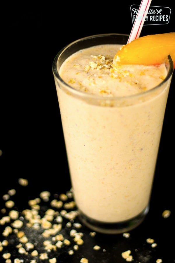 Peaches and Cream Oatmeal Smoothie in a tall glass with a peach slice on the rim.