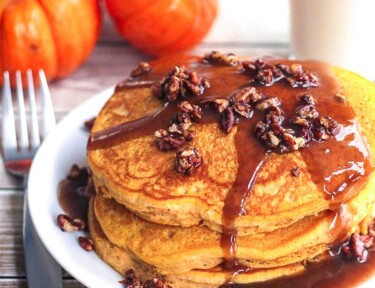 A stack of pumpkin pancakes with a pecan caramel syrup on top