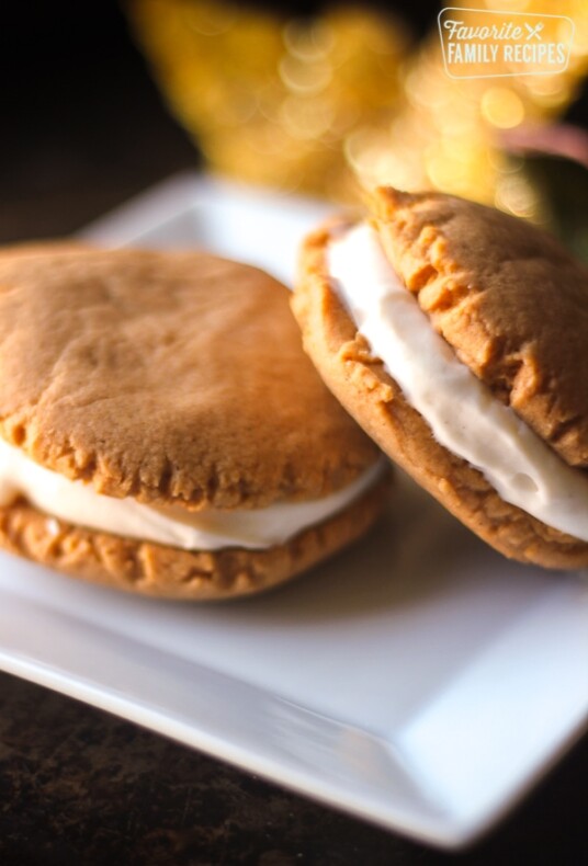 Pumpkin sandwich cookies on a white plate.