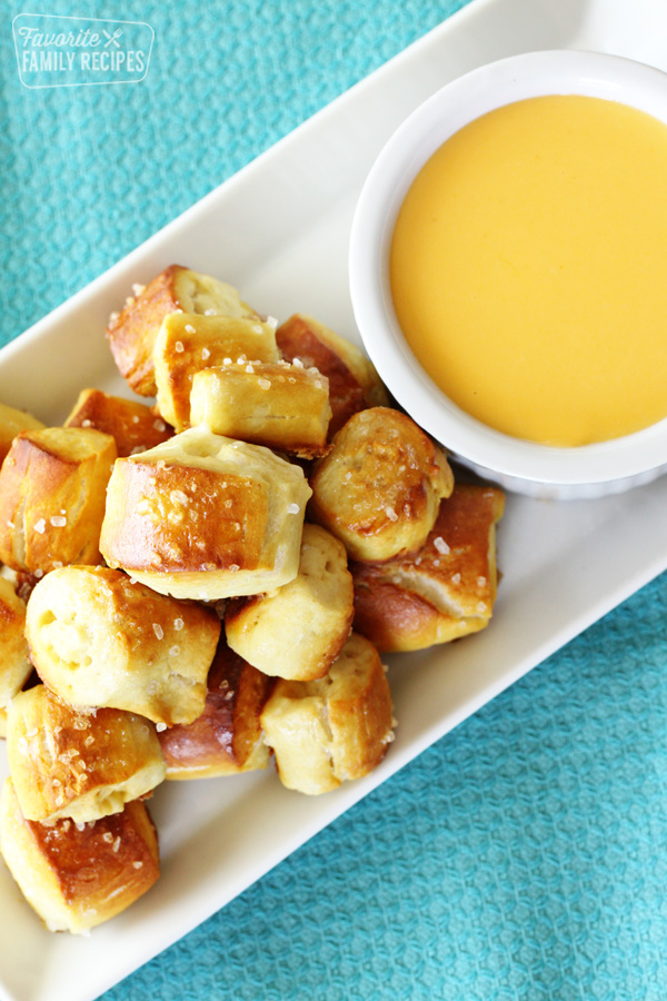 Small pretzel bites on a plate next to cheese dip.