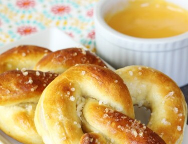 Perfectly golden soft pretzels on a plate with cheese sauce