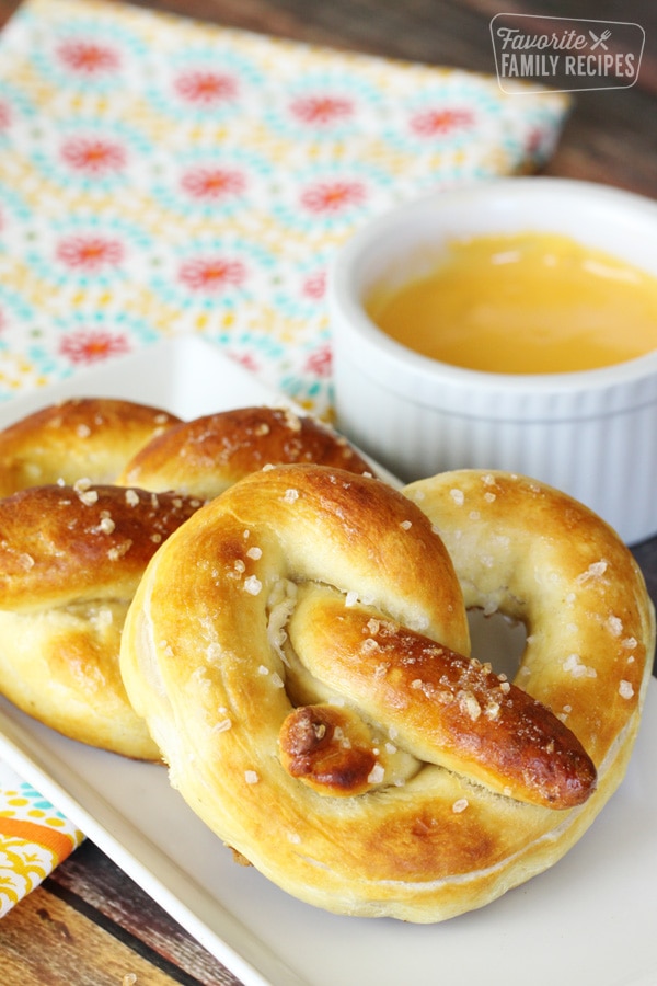 Perfectly golden soft pretzels on a plate with cheese sauce.