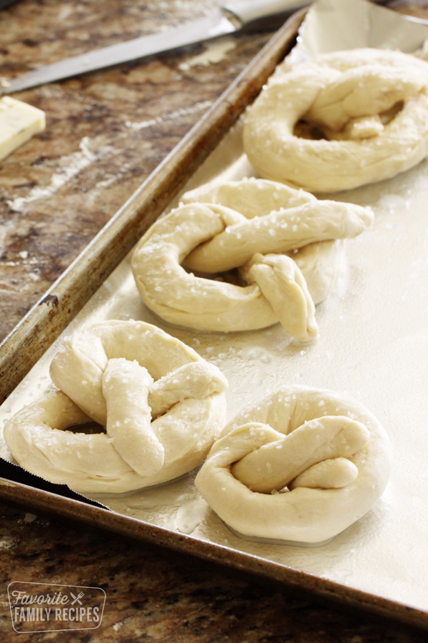 Uncooked soft pretzels on a baking sheet.