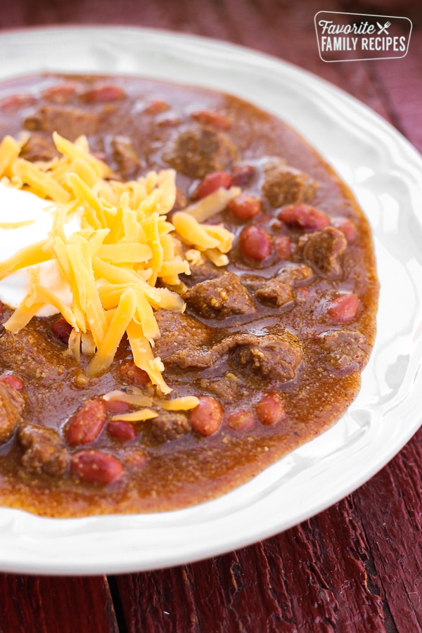 Chili with cheese and sour cream on top in a white bowl. 