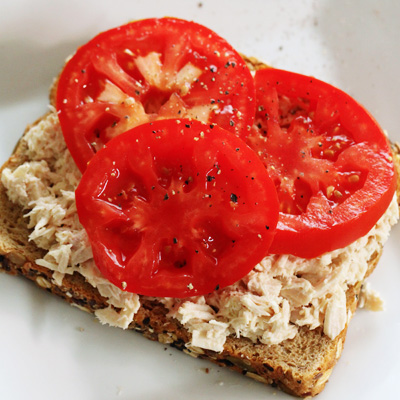 Slice of whole wheat bread layered with tuna fish and tomatoes