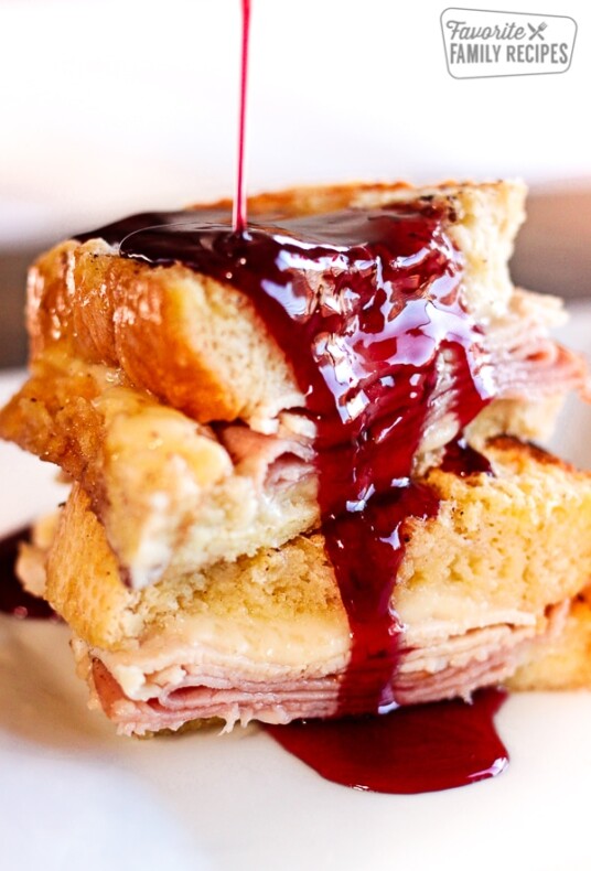 Baked Monte Cristo French Toast with dark red Syrup Pouring on Top
