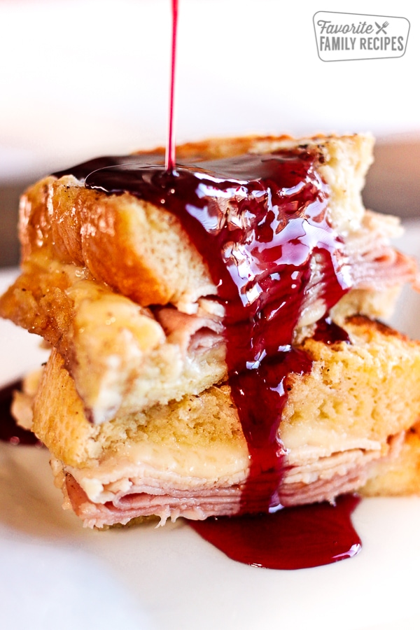 Baked Monte Cristo French Toast with dark red Syrup Pouring on Top