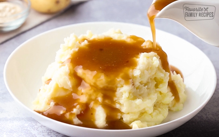 Pouring beef gravy over mashed potatoes