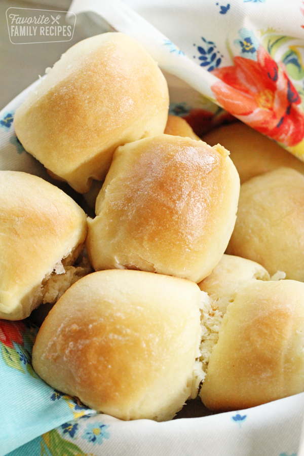 Soft buttery dinner rolls in a basket with a decorative cloth
