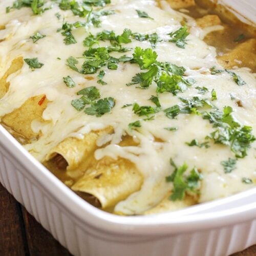 Many Cafe Rio burritos in a dish, smothered with sauce and cheese