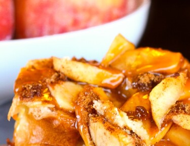 Caramel Apple French Toast on a plate with a bowl of apples in the background.