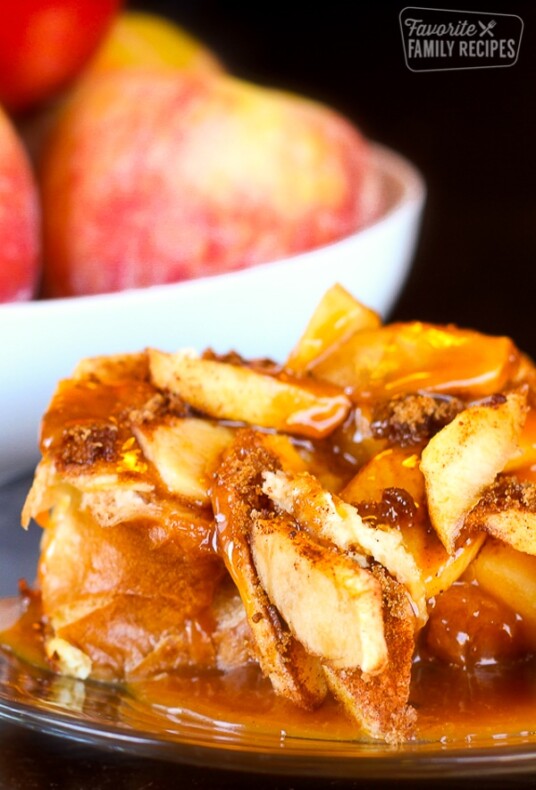 Caramel Apple French Toast on a plate with a bowl of apples in the background.