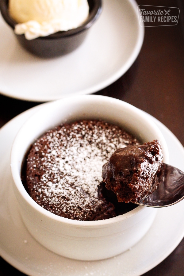 Carnival Cruise Line Warm Chocolate Melting Cake in a small white bowl with powdered sugar being scooped out on a spoon.