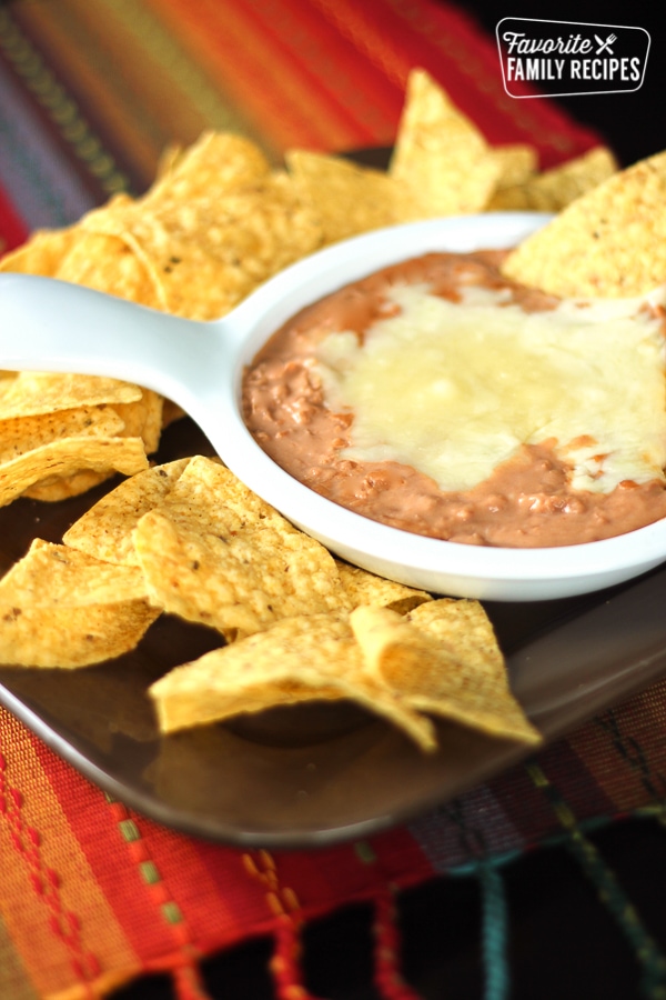 Cheater Restaurant Style Refried Beans in a white bowl surrounded by tortilla chips.