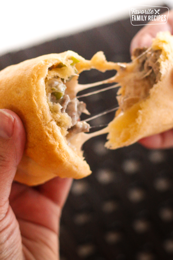 Cheesesteak Crescent Roll being torn into two pieces.