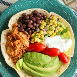 Chicken Taco Salad in a Tortilla Bowl with corn, beans, avocado, tomatoes, and sour cream in a blue bowl