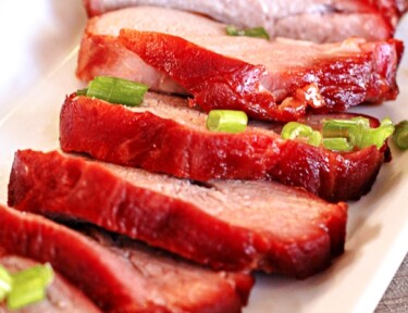 6 slices of Chinese BBQ Pork with green onions on a white tray