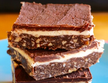 3 Coconut Pecan Nanaimo Bars stacked on top of each other on a blue plate