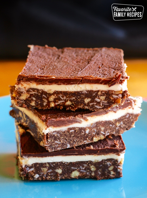 3 Coconut Pecan Nanaimo Bars stacked on top of each other on a blue plate