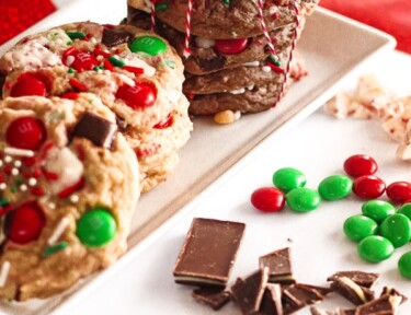 Elf Cookies stacked on top of each other with christmas candy scattered around them.
