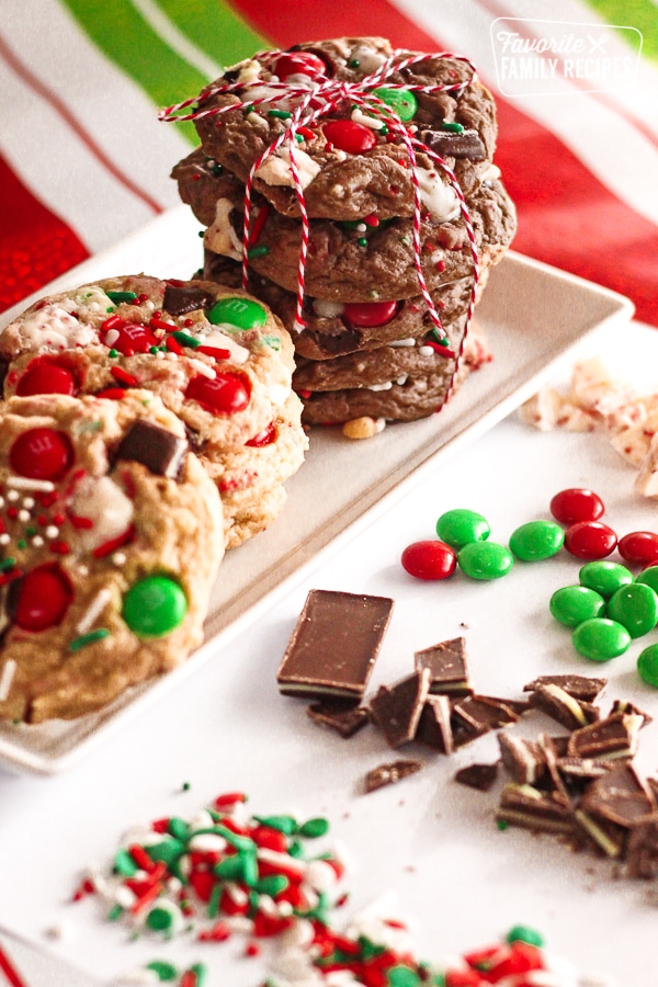 Elf Cookies stacked on top of each other with christmas candy scattered around them.