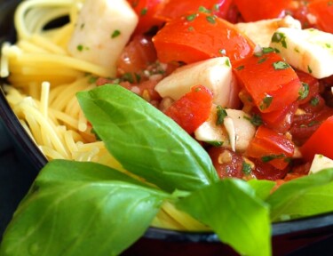 Close up of Fresh Tomato and Basil Pasta in a black bowl.