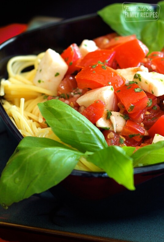 Close up of Fresh Tomato and Basil Pasta in a black bowl.