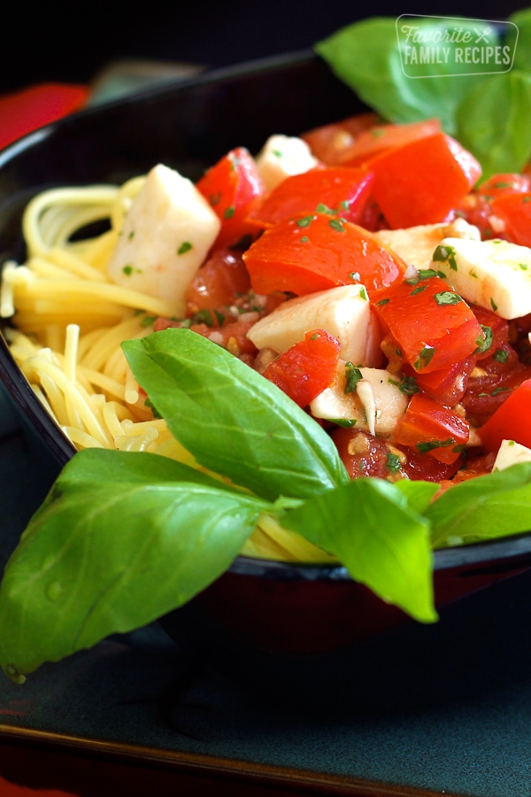 Close up of Fresh Tomato and Basil Pasta in a black bowl.